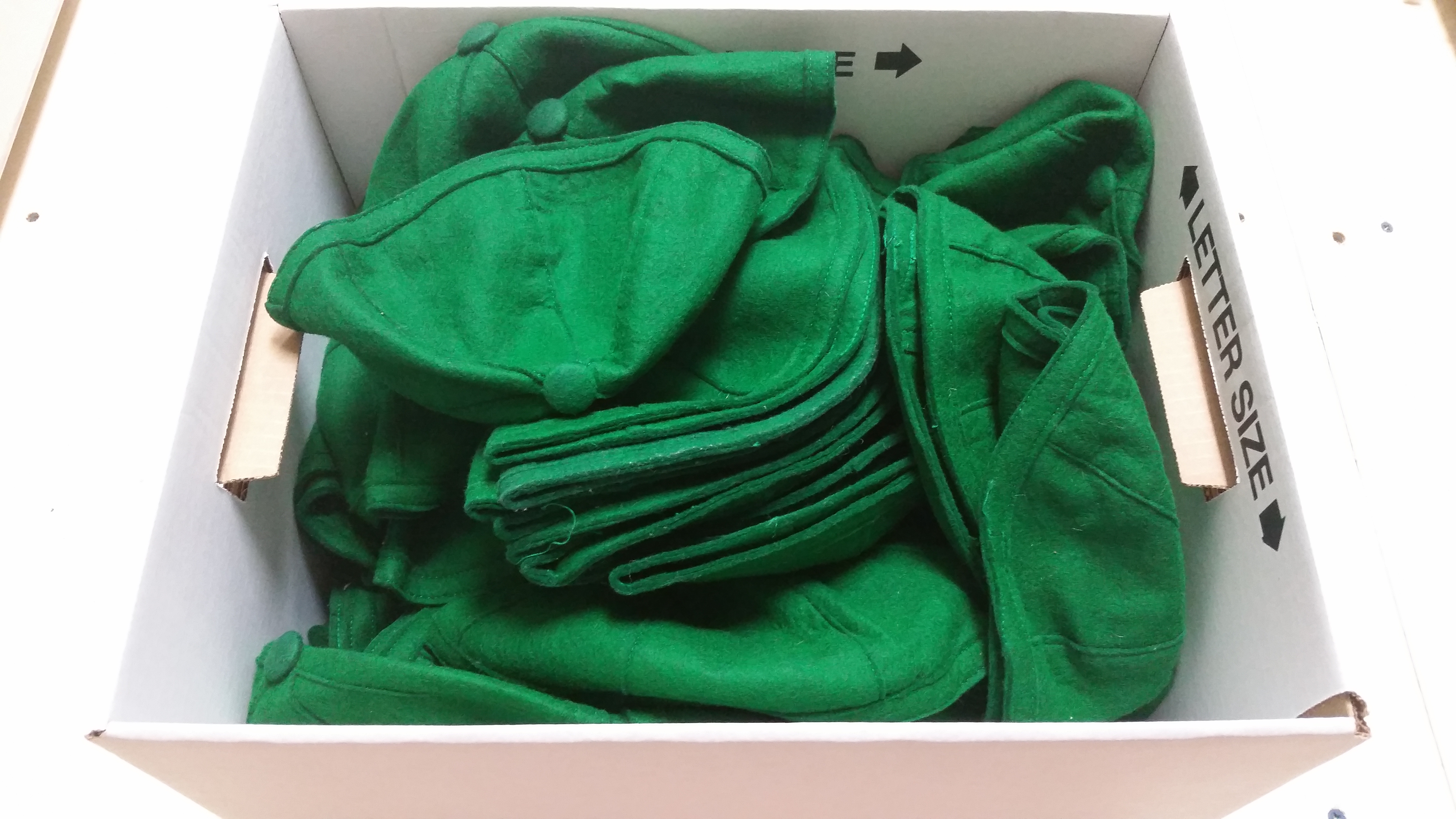 cardboard box full of green felt beanies from Nash Library archives